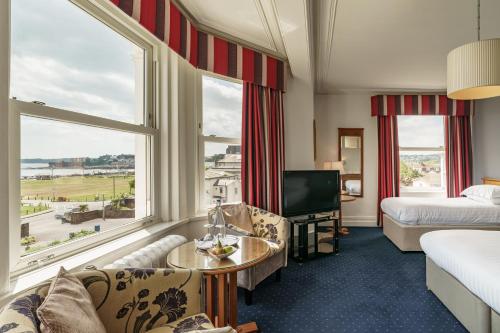 a hotel room with a bed and a couch and a tv at The Palace Hotel in Paignton