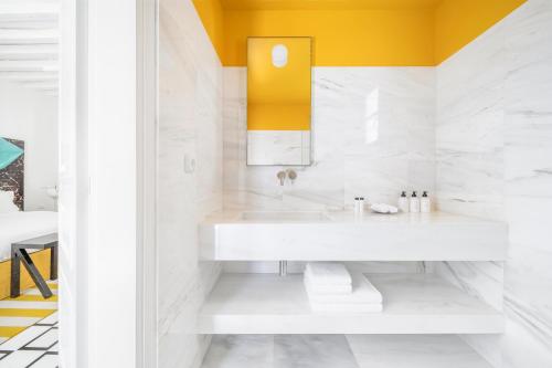 a white bathroom with a sink and a yellow wall at ANEMI Folegandros in Karavostasi
