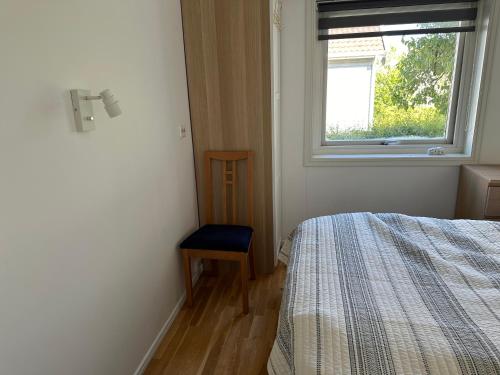 a bedroom with a bed and a window and a chair at Mandal Apartment mit Möglichkeit ein Boot zu benutzen und Angeln in Mandal