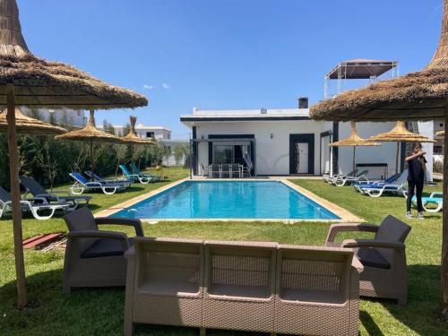 eine Villa mit einem Swimmingpool mit Stühlen und Sonnenschirmen in der Unterkunft Villa campagne bouznika in Bouznika