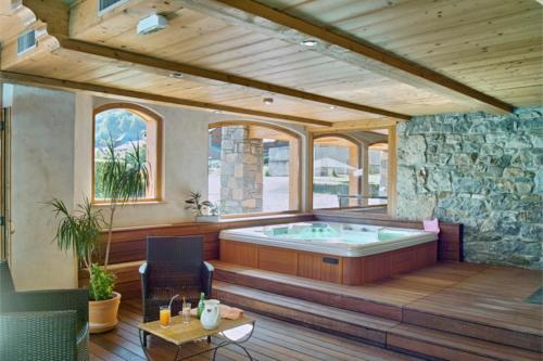 un bain à remous dans une pièce avec un mur en pierre dans l'établissement Le Morillon - Piscine et Spa, à Morillon