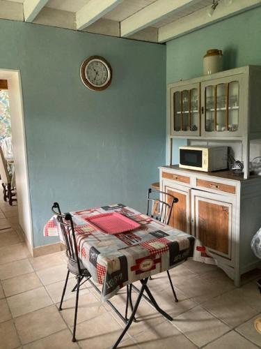 une cuisine avec une table et une horloge au mur dans l'établissement GITE EQUESTRE DE LA LANDE, à Bréhal