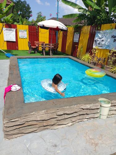 a young girl in a swimming pool with a frisbee at Hana Homestay Kolam Terengganu in Marang