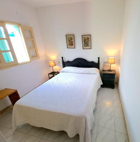 a bedroom with a white bed and two lamps at Casa Belén in Pozo Negro