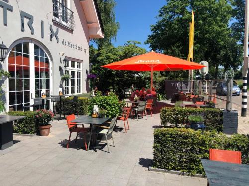 a patio with tables and chairs and an umbrella at Hotel Trix in Arnhem