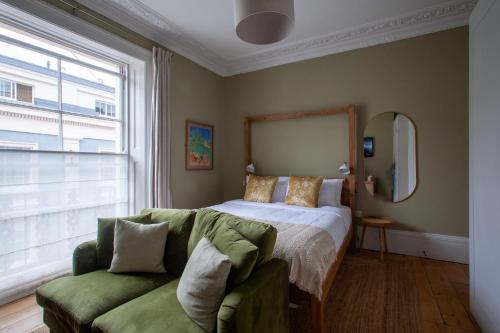 a bedroom with a bed and a green couch at Lido Townhouse in Bristol
