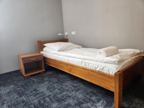 a small bedroom with a bed and a night stand at Dom Pielgrzyma w Kodniu in Kodeń