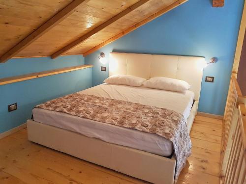 奥梅尼亚Canova Piano Primo - Cosy Studio Lake Orta Area的蓝色墙壁和木地板的客房内的一张床位