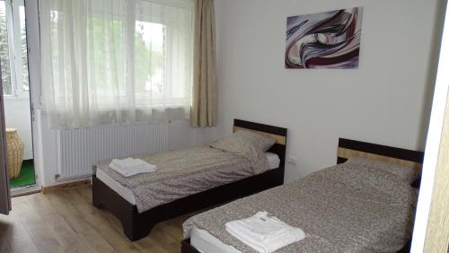 two beds in a small room with a window at M Family Apartment in Odorheiu Secuiesc