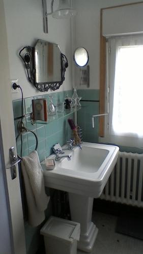 une salle de bain avec un lavabo et un miroir au mur dans l'établissement Chaleureuse maison bretonne, à Pleubian