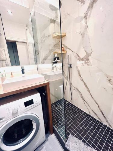 une machine à laver dans une salle de bain avec douche dans l'établissement La Garenne Colombes proche La Défense et idéal Jeux Olympiques, à La Garenne-Colombes