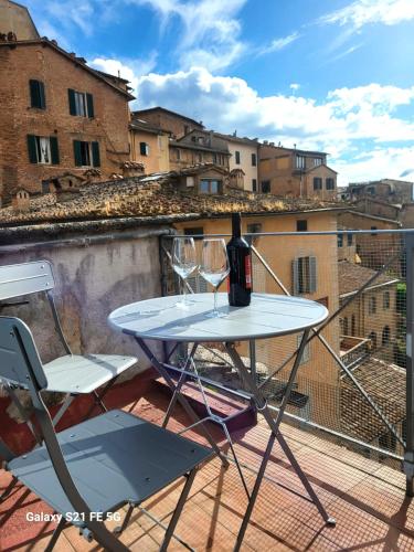 a table with a bottle of wine sitting on a balcony at Alba -vista unica con terrazza- in Siena