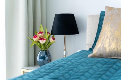 a vase of flowers sitting on a bed with a lamp at Your Holidays Waves in Międzyzdroje