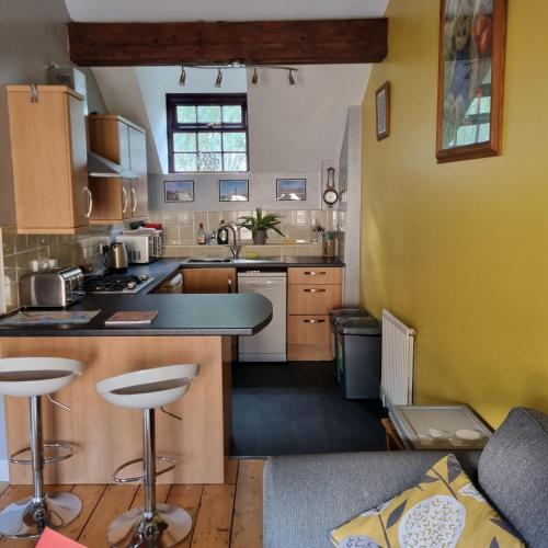a kitchen with a counter and some stools in it at Primrose Cottage in Plymouth