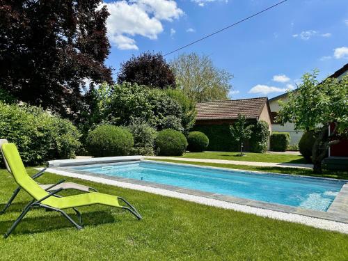 a green chair sitting in the grass next to a swimming pool at Sous le Cerisier in Venarey-les-Laumes