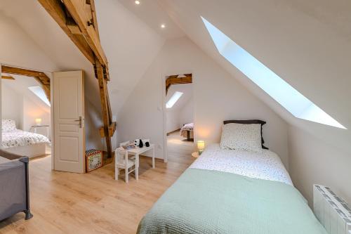 - une chambre mansardée avec un lit et une télévision dans l'établissement La Maissemiacoise - Belle Maison de campagne, à Maissemy