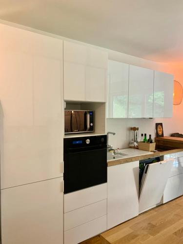 une cuisine avec des armoires blanches et un micro-ondes dans l'établissement Appartement rénové en bordure de forêt, à Clamart