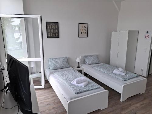 una camera con due letti e una TV a schermo piatto di CityOase Magdeburg Studios am Königsweg, Studio 4, WiFi, Stellplatz, Netflix a Magdeburgo