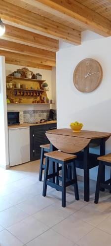 une cuisine avec une table en bois et une horloge au mur dans l'établissement Kilomètre Creusois, à Saint-Dizier-Leyrenne