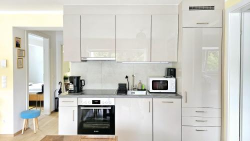 a white kitchen with a stove and a microwave at "Casa Antonio" 3 Gehminuten Strandbad Sekirn, inkl Seezugang in Sekirn