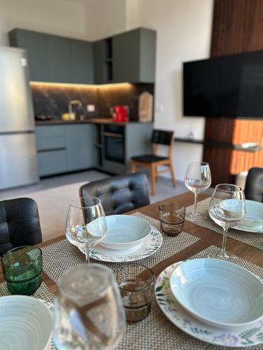 a table with plates and wine glasses on it at OLEA Family Apt with Garden in Dhërmi