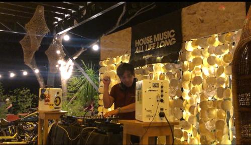 a man standing behind a counter in a room with a dj at Cafe Moto Hostel in Puerto Princesa City