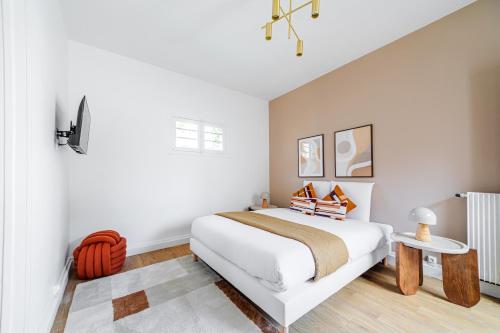 a white bedroom with a bed and a table at Studio proche Paris Expo Porte de Versailles in Issy-les-Moulineaux
