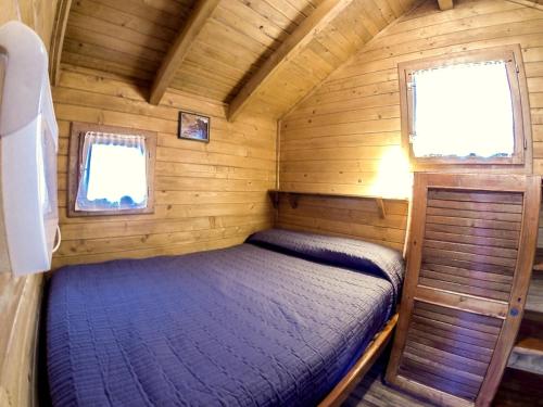 a bedroom in a log cabin with a bed in it at Camping Bedura Park in Era Bordeta
