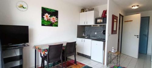 une cuisine avec une table et des chaises et une télévision dans l'établissement Sala P, à Valras-Plage