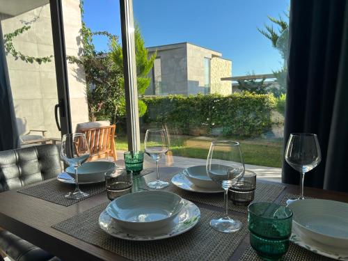 un tavolo con piatti e bicchieri da vino sopra di OLEA Family Apt with Garden a Dhërmi