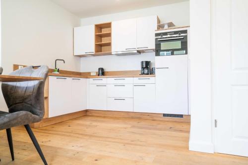 a kitchen with white cabinets and a wooden floor at Traumgarten Haus Unschuld in Prerow