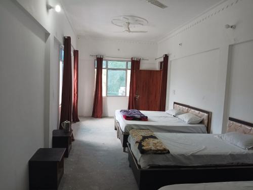 a room with three beds in it with windows at Vasudhara Hotel & Restaurant in Pīpalkoti