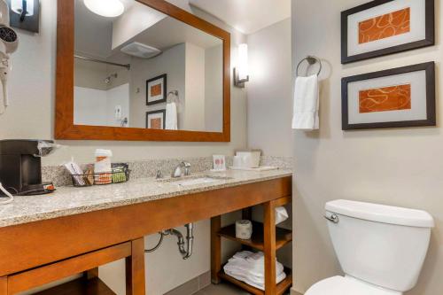 a bathroom with a toilet and a sink with a mirror at Comfort Suites Redding - Shasta Lake in Redding