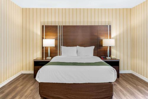 a large bed in a hotel room with two lamps at Quality Hotel & Suites in Sherbrooke