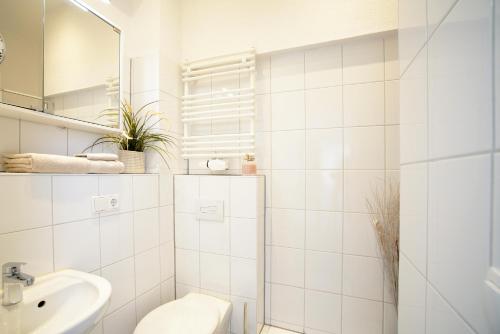 a white bathroom with a toilet and a sink at Apartments am Schlosspark in Senftenberg