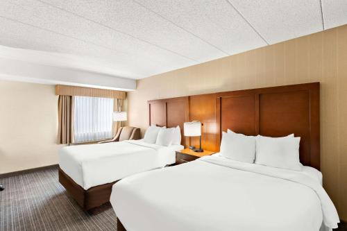 two beds in a hotel room with white sheets at Comfort Inn White River Junction in White River Junction