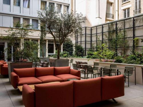 a couch sitting on a patio with tables and chairs at Mercure Paris 17 Batignolles in Paris
