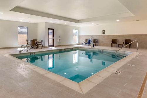 a pool in a hotel with chairs and tables at Comfort Suites Albuquerque Airport in Albuquerque