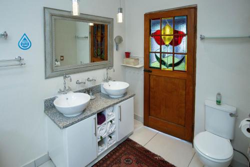 a bathroom with two sinks and a mirror and a toilet at Oleander Guest House in Kimberley