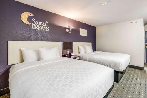 two beds in a hotel room with purple walls at Clarion Pointe Tallahassee-State Capitol in Tallahassee