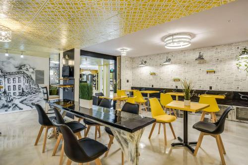 a dining room with yellow chairs and a table at Clarion Pointe Tallahassee-State Capitol in Tallahassee