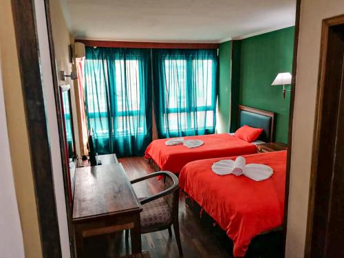 una camera d'albergo con due letti con lenzuola rosse e un tavolo di Big Bang Hôtel Behoririka a Antananarivo
