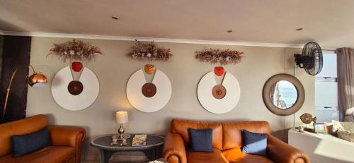 a living room with a couch and a wall with hats at Crystal Lagoon Lodge in Langebaan