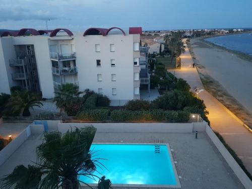 - une piscine en face d'un bâtiment à côté de la plage dans l'établissement Superbe appartement vue Mer - Gruissan 6LB42, à Gruissan