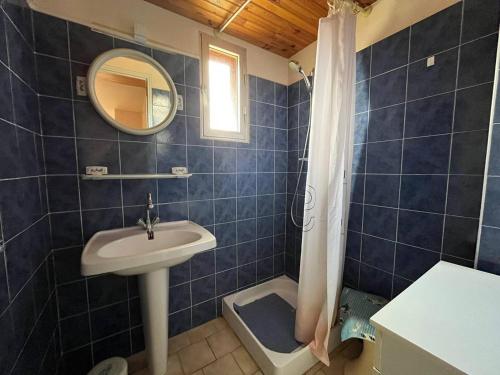 La salle de bains est pourvue de carrelage bleu, d'un lavabo et d'un miroir. dans l'établissement Appartement T3 idéal pour une famille avec parking 4GEN5, à Saint Pierre La Mer