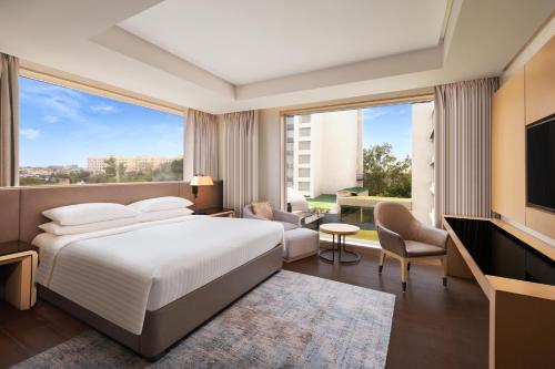 a hotel room with a bed and a large window at Indore Marriott Hotel in Indore