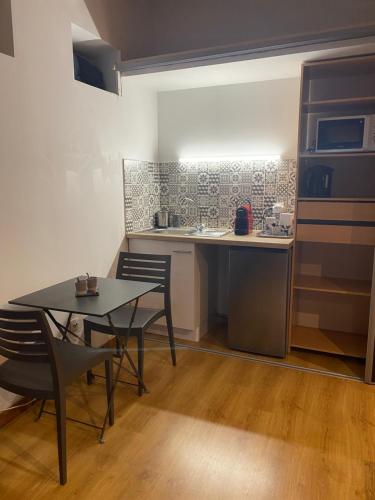 - une petite cuisine avec une table, des chaises et un comptoir dans l'établissement Studio indépendant avec piscine partagée, à Marseille