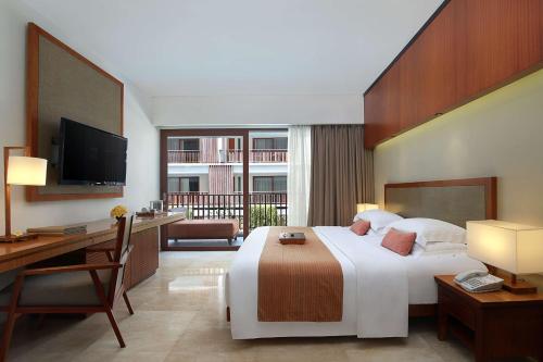 a hotel room with a bed and a desk and a television at The Magani Hotel and Spa in Legian