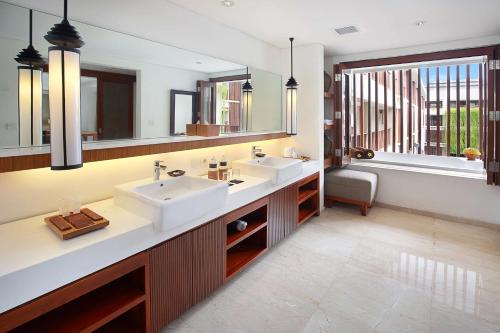 a bathroom with two sinks and two mirrors at The Magani Hotel and Spa in Legian