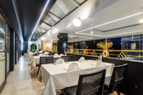 a dining room with white tables and chairs at Pansion Zlatna ribica in Brodarica